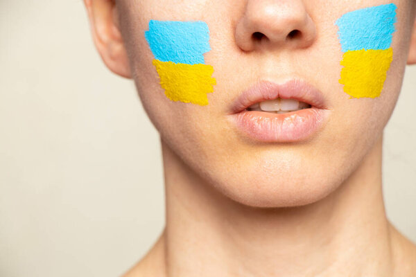 The face of a girl with the national flag of Ukraine yellow-blue on her face, patriot, peace in Ukraine, martial law