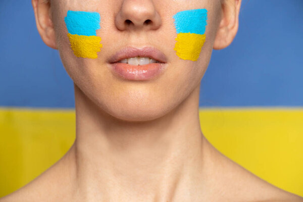 The face of a girl with the national flag of Ukraine yellow-blue on her face, patriot, peace in Ukraine, martial law