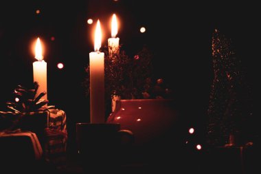 Yılbaşı hediyeleri, cila ve mumlarla dolu bir masa. Karanlıkta dekoratif küçük bir Noel ağacı taşıyorlardı. Mutlu yıllar.