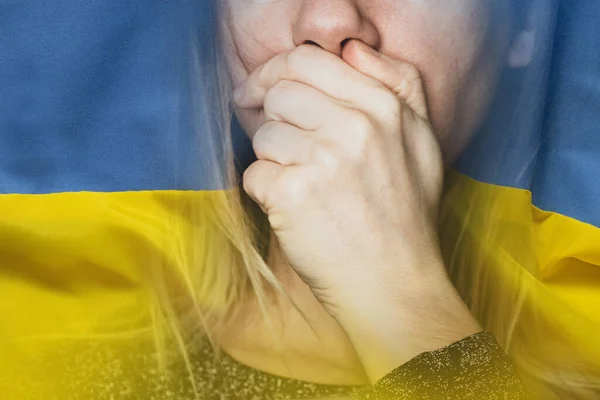 Stop the war in Ukraine. The girl covered her mouth with her hand against the background of the flag of Ukraine, War in Ukraine, protest action, civilians, do not be silent and tell everyone