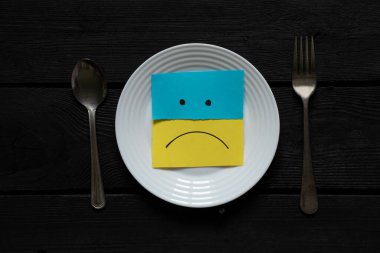 Ukrayna 'nın sarı-mavi milli bayrağı bir tabakta yatıyor, hüzünlü duygular, Ukrayna' daki savaş, savaşı durdurmak, yas tutmak, açlık, yiyecek bir şey yok.