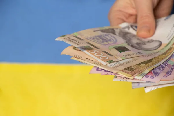 Ukrayna ulusal bayrağı, Ukrayna finans ve ekonomisinin arka planına karşı Ukrayna 'da bir kadın eli tutuyor.