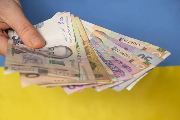 Ukrayna ulusal bayrağı, Ukrayna finans ve ekonomisinin arka planına karşı Ukrayna 'da bir kadın eli tutuyor.