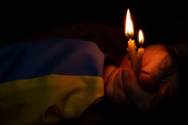 Büyükannem Ukrayna için dua ediyor ve Ukrayna bayrağı ve bir mum taşıyor, Ukrayna 'da savaş, ülkesi için dua, savaş yok, herkese barış. Savaşı durdurun 2022