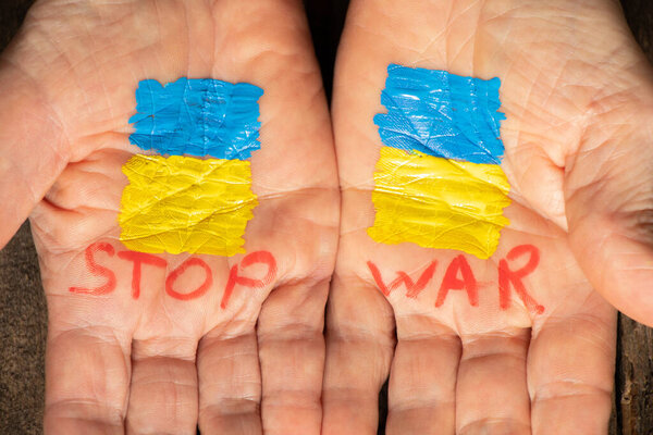 On the hands of the old woman is drawn the yellow-blue flag of Ukraine and the words stop the war, Stop the war and patriotism, peace in Ukraine, stop the war in Ukraine. Peace to all, the flag of Ukraine. Protest