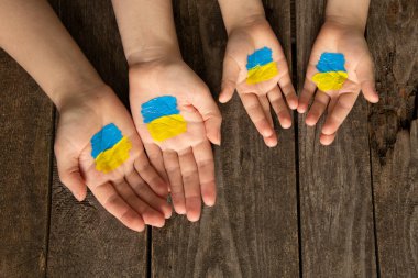 Ukrayna 'nın sarı-mavi bayrağını taşıyan anne ve çocuğun elleri. Ukrayna 'da sıkıyönetim 2022. Savaşı ve barışı durdurun, barışçıl insanlar Ukrayna, protesto eylemi, barışçıl aile