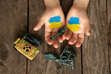 Ukrayna 'nın sarı-mavi bayrağı bir çocuğun ellerinde, askerler ve tank yan yana uzanıyor, Ukrayna' da Rusya ile savaş, Ukrayna 'da barış, Ukrayna' daki savaşı durdurmak için.