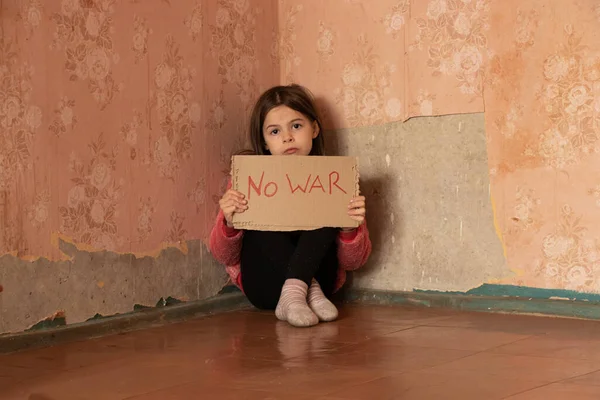 A little girl holds a poster with the words stop the war at her home in Ukraine and asks to stop the war in Ukraine, the children ask, a protest action