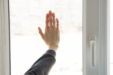 Gündüz vakti kadın elleri evin penceresinde, güneş ışığında.