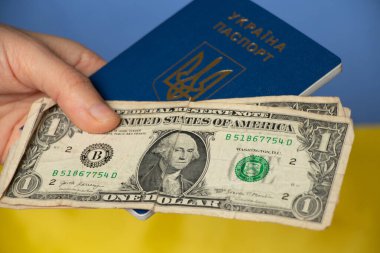 Bir kadının elinde yabancı bir pasaport ve dolarla Ukrayna bayrağı, göç ve seyahat
