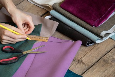Kadın elleri masadaki farklı kumaş parçalarını kesiyor, terzi atölyesi, dikiş ve moda, terzilik.
