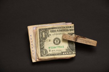 Kara bir zemin, gelir ve yatırım, finans ve ekonomi üzerine ahşap bir mandal altında para dolarları ve Hryvnia