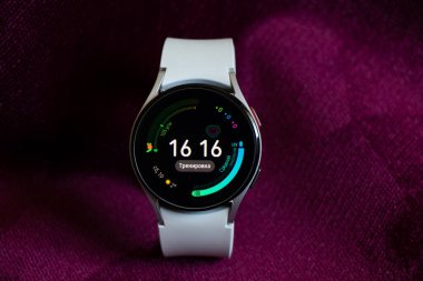 Ukrayna Dnepr 19.03.2022 - Akıllı saat Samsung Galaxy 4.40 mm kadınlar için beyaz bir kayış üzerinde masanın üzerinde kırışık kumaş, teknolojiler