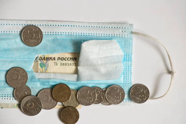俄罗斯卢布，背景是白色的，戴着医疗面具，在俄罗斯的金钱、医药和金融上都有漏洞 — 图库照片