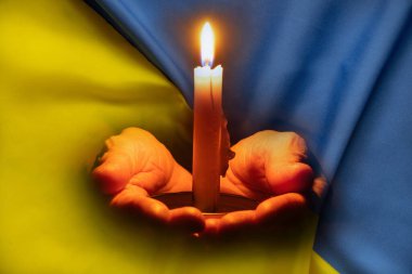 Ukrayna 'daki savaşı durdurun. Elinde mumla Ukrayna bayrağı, Ukrayna 'da savaş, protesto eylemi, siviller, Ukrayna 2022 için dua eden bir kız.