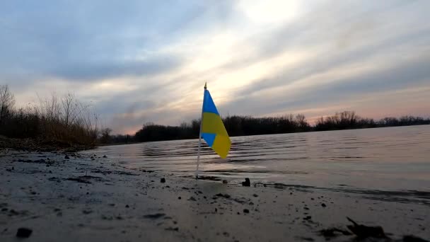 A bandeira nacional da Ucrânia nas margens do rio Dnieper ao vento ao amanhecer na Ucrânia, o país livre e independente da Ucrânia, a bandeira ucraniana ao vento — Vídeo de Stock