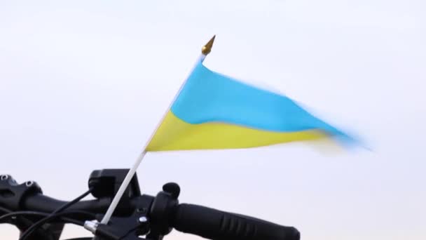 Le drapeau national de l'Ukraine, jaune et bleu, se tient sur le guidon d'un vélo dans le vent dans une ville en Ukraine, arrêter la guerre en Ukraine, les gens libres — Video