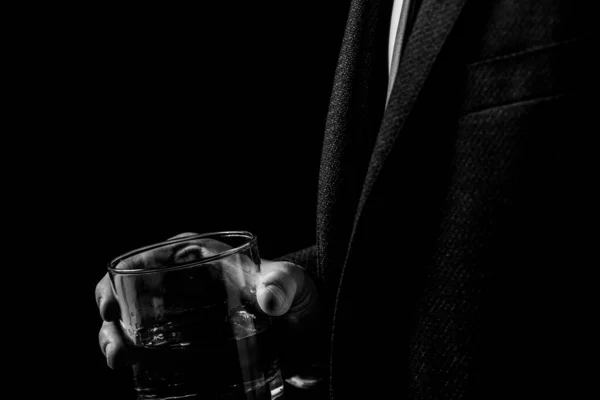 暗闇の中でスーツを着た男の手にウィスキーのガラス男は酒を飲み黒と白の写真 — ストック写真