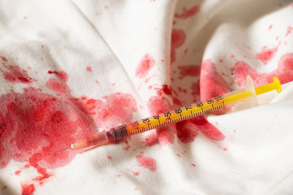 Blood stains on a white dress and a syringe, treatment and medicine