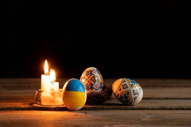 Ukrayna bayraklı tavuk yumurtası boyası ve Ukrayna 'daki evdeki masada mum alevi savaş sırasında Ukrayna' da Paskalya tatili.