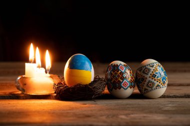 Ukrayna bayraklı tavuk yumurtası boyası ve Ukrayna 'daki evdeki masada mum alevi savaş sırasında Ukrayna' da Paskalya tatili.