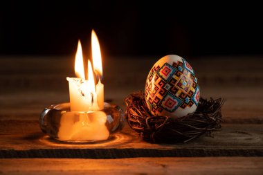 Ukrayna demokrasi yumurtası ve şamdanın içindeki mum Ukrayna 'da 2022 savaşında, karanlıkta, Paskalya bayramında evdeki bir masada.