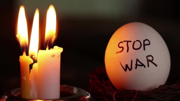 在乌克兰的黑暗 和平与文化中 在点燃的蜡烛旁边躺着一只鸡的白蛋 上面写着 停止战争 — 图库视频影像