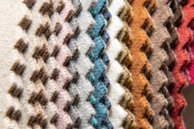 Müşterinin döşeme seçimi için farklı renk kumaş kataloğu, arka plan olarak çok renkli kumaş örnekleri, atölyedeki moda trendi kumaşları