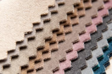 Müşterinin döşeme seçimi için farklı renk kumaş kataloğu, arka plan olarak çok renkli kumaş örnekleri, atölyedeki moda trendi kumaşları