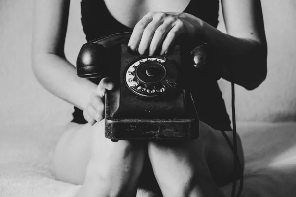 Velho telefone retro preto nas pernas de uma mulher close-up, uma chamada para o telefone — Fotografia de Stock