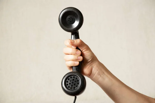 Una mano di donne tiene un telefono vecchio tubo nero su uno sfondo bianco, chiamata — Foto Stock