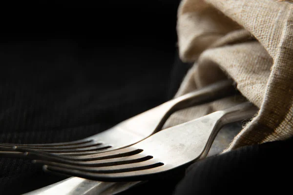 ナプキンに包まれたヴィンテージの古いフォークとナイフは テーブルの上の黒いテーブルクロスに横たわっています — ストック写真