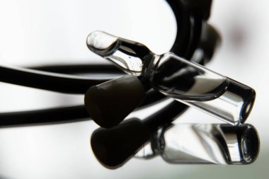 İlaçlı bir ampul ve steteskop karanlıkta aynanın üzerinde duruyor, ilaç ve uyuşturucu makro fotoğraf.