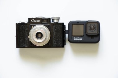 Ukrayna Dnepr 28.04.2022 - Smena kamera - SSCB 1952, Sovyet kamera koleksiyonu ve beyaz arkaplanda GoPro HERO 9 siyah video kamera