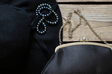 Siyah kadın şapkası ve siyah bir akşam çantası ve ahşap bir masa üzerinde inci boncuklar, moda ve trend, güzellik ve aksesuarlar