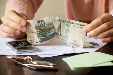 Kadınların elleri raporlarla dolu bir masada on ruble yırttı. Yaptırımlar nedeniyle Rusya 'da temerrüt. Ruble 2022' nin çöküşü.