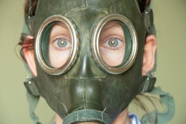 Yeşil arka planda Sovyet yeşil gaz maskeli bir kızın yüzü, gaz maskesi, gaz saldırısı, klasik gaz maskesi.