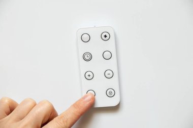 Beyaz arka planda uzaktan kumanda. Uzaktan kumandaya bas, düğmeye bas.