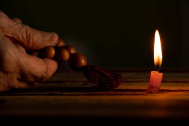 A woman with a wooden rosary and a bible vomited candles in the dark, a woman prays, praying, faith and religion,temple