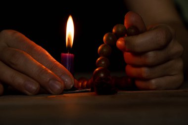 A woman with a wooden rosary and a bible vomited candles in the dark, a woman prays, praying, faith and religion,temple