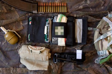 Ukraine Dnipro 09.05.2022 - A first aid kit of a military soldier and a grenade a bullet in a horn and a helmet in Ukraine in the war lies on a camouflage net, an ambulance, a military weapon