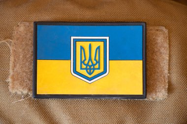 Ukrayna 'nın sarı ve mavi ulusal bayrağı bir askerin yeşil üniformasında, 2022 Ukrayna' daki savaşı ve barışı durdurun, 2022 Ukrayna askerinin üniformasında askeri rozet