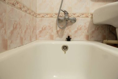 Konut binasında bir banyo, küvetten fayansa kadar manzara ve duvarda bir musluk.