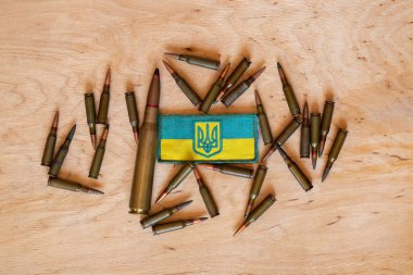 Pili tahta bir arka planda yatıyordu ve yanında Ukrayna bayrağı, Ukrayna 'daki savaş, mühimmat ve silahlarla birlikte bir yama yatıyordu.