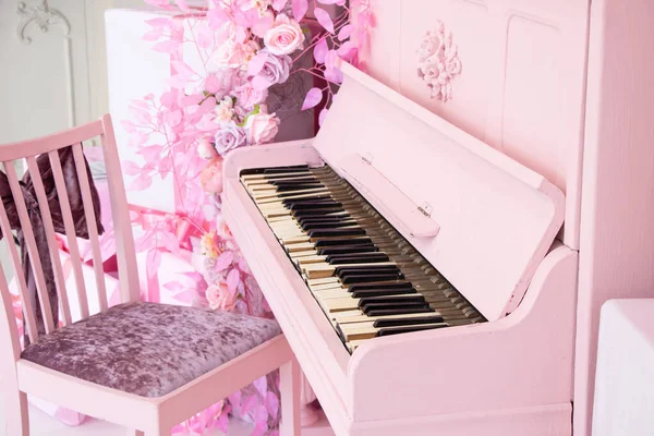 A pink piano and a pink chair in the room, a musical instrument, old piano keys