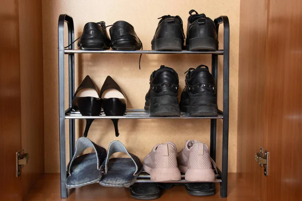 A shelf with shoes in the closet, sneakers, sneakers and shoes are on the shelf in the hallway, womens worn shoes, a pair of old shoes