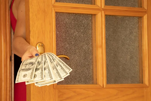 Женская Рука Протягивает Доллары Дверям Дома Давая Деньги Через Дверь — стоковое фото