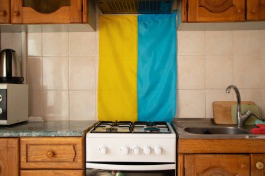 Ukrayna bayrağı Ukrayna 'da bir apartmanın mutfağındaki duvarda bir gaz ocağının, Ukrayna' daki savaşın arka planında asılı.