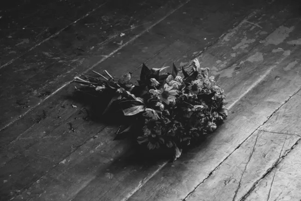 A bouquet of wild flowers lies on the floor of the house black and white photo, flowers on the floor