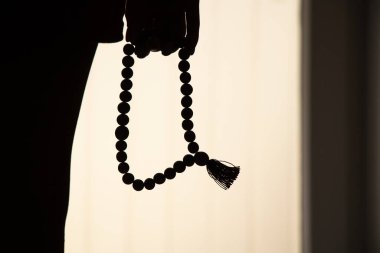 Rosary in the hands of a woman in the dark, faith and religion, pray